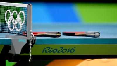 Table tennis paddles rest on a table.