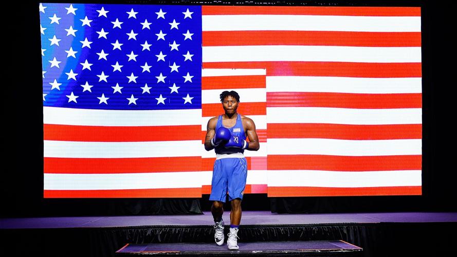 Jahmal Harvey walks out in front of LED screen showing U.S. flag