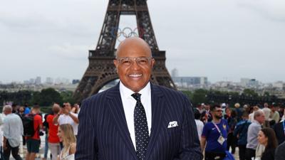 Mike Tirico poses near the Eiffel Tower during the Paris Olympic Games